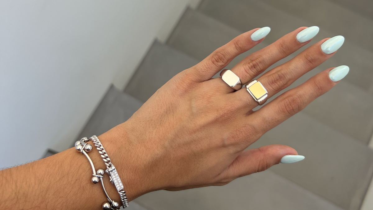 Hand with summer nail art colors featuring turquoise nails and stylish rings from CINCO Jewelry.