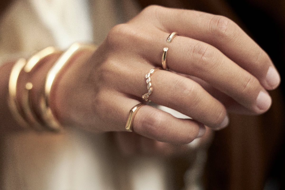 Elegant hand showcasing multiple gold rings, illustrating ring stacking fashion tips.