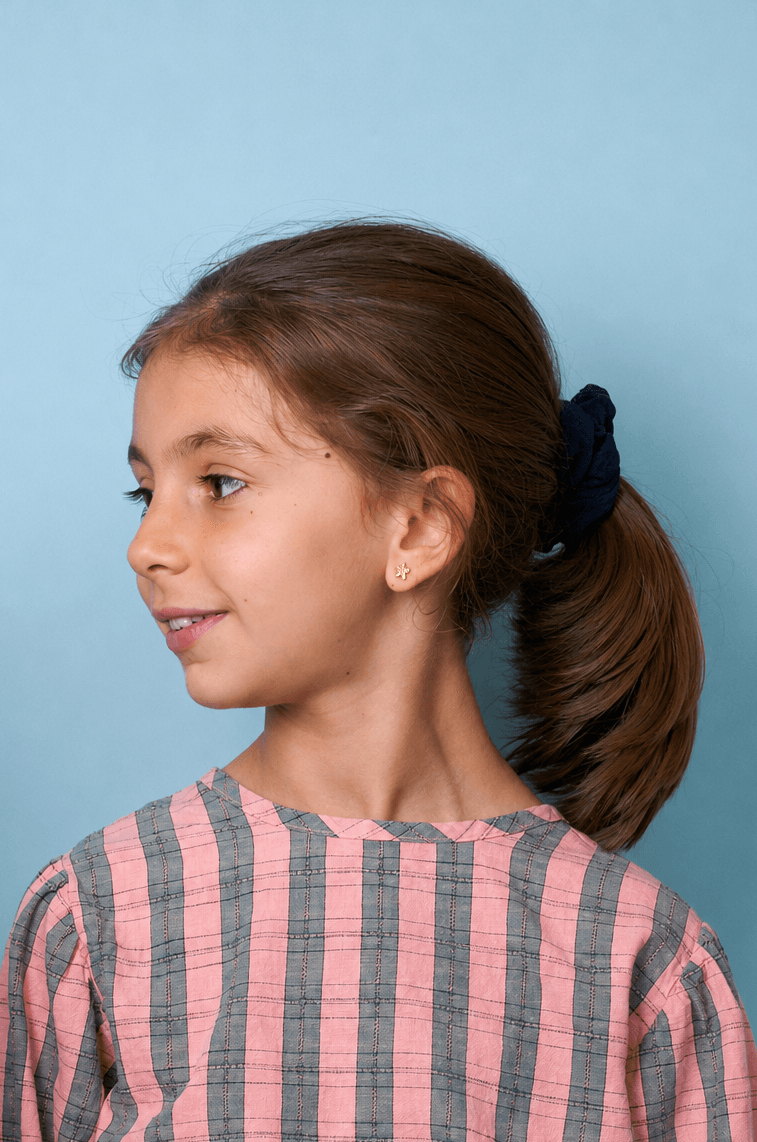 Junges Mädchen trägt ein rosa-grau gestreiftes Shirt vor blauem Hintergrund