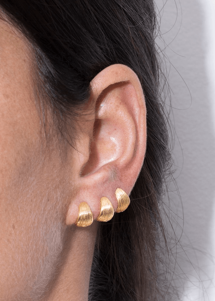 Tilly huggie earrings silver gold worn on model's ear showcasing the unique design and gold plating details.