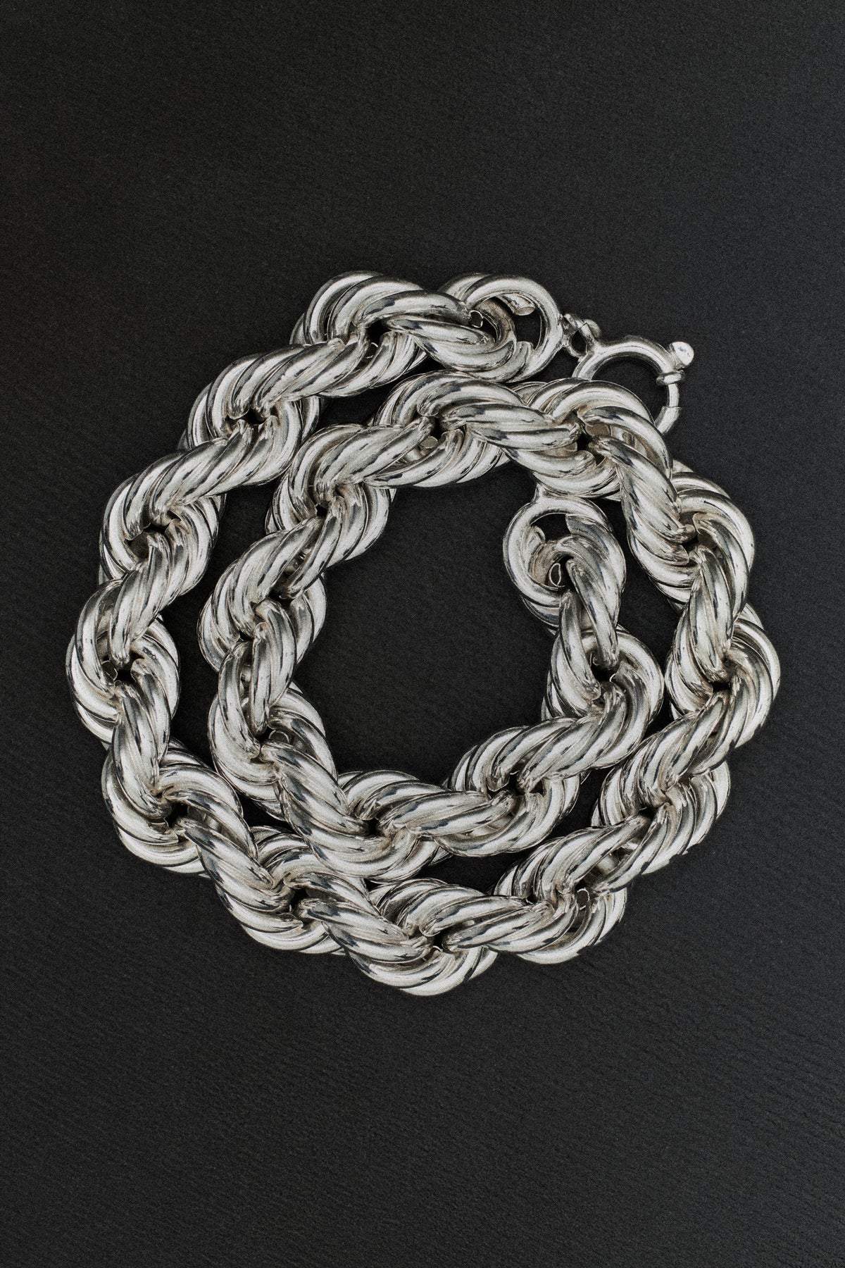Silberne Halskette mit Kette vor schwarzem Hintergrund