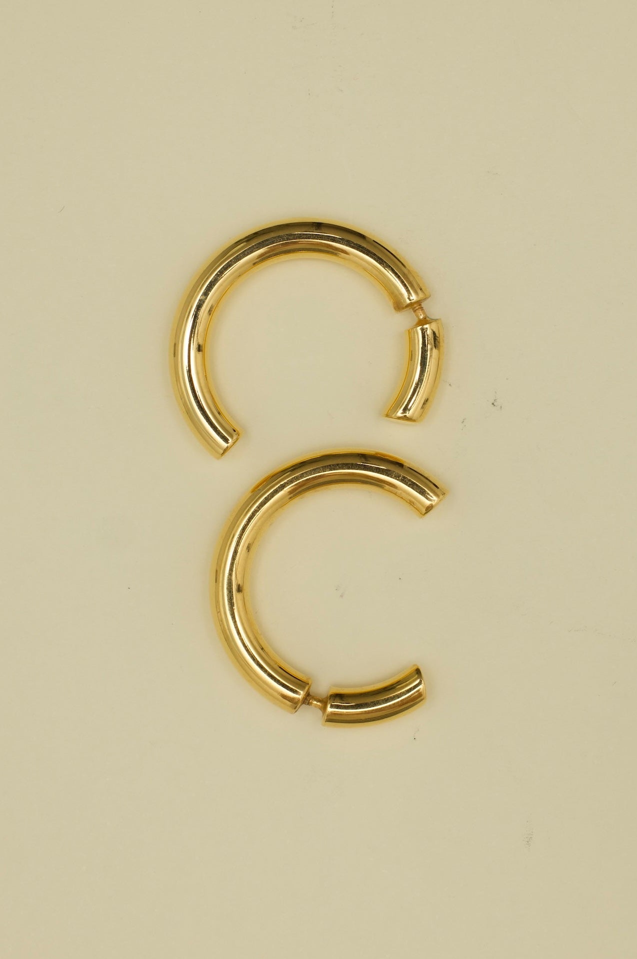 Gold hoop earrings on a beige background