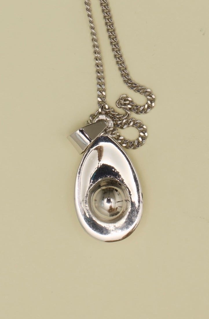 Silver necklace with a teardrop pendant on a beige background