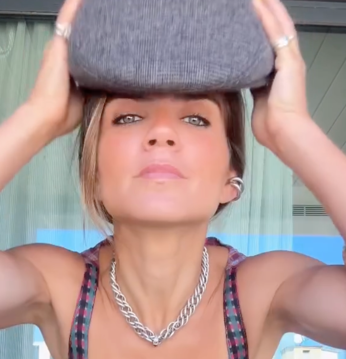 CINCO model showcasing a gray handbag in a sunny setting, wearing a chunky silver necklace.