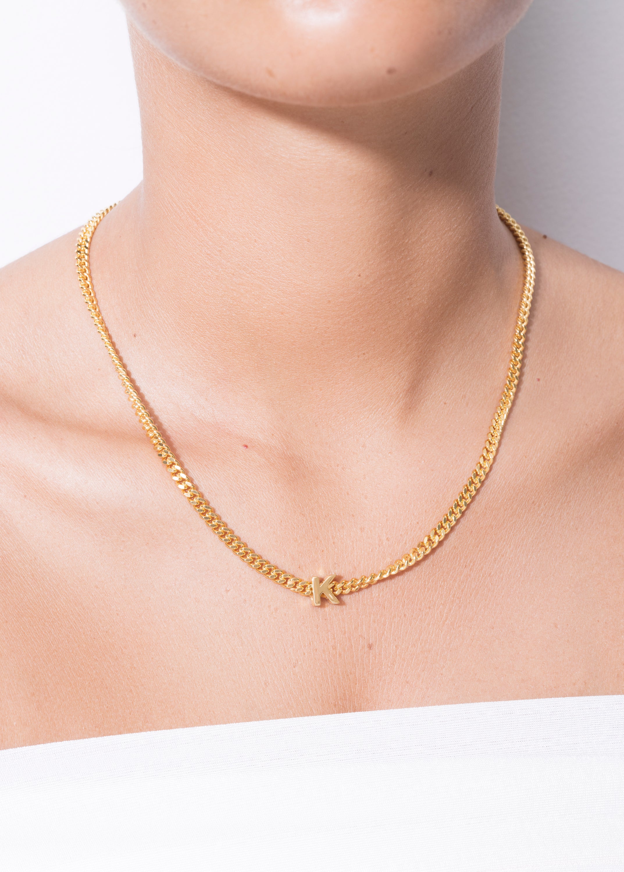 model wearing alphabet necklace with pendant K in gold