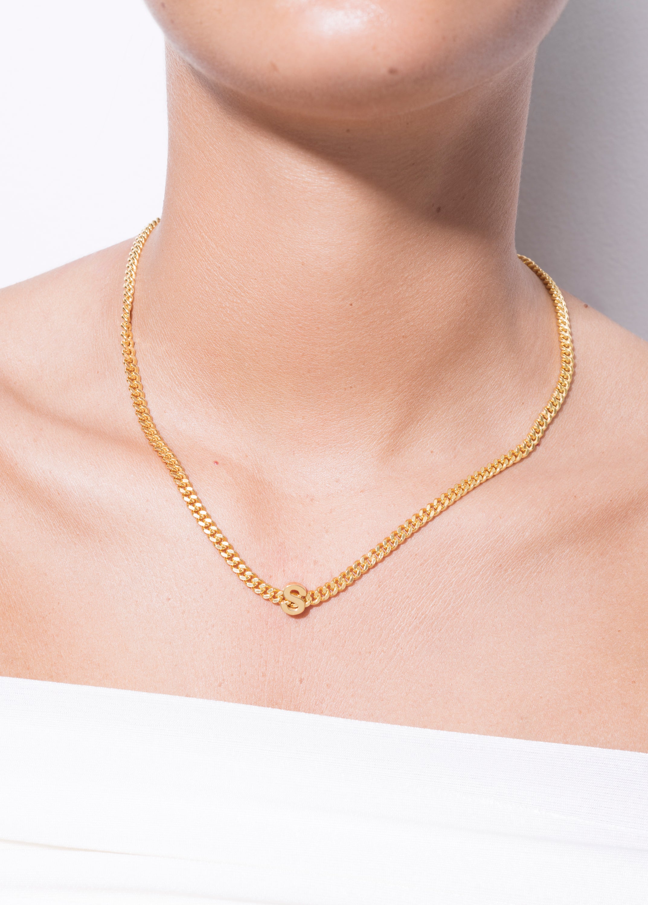 model wearing alphabet necklace with pendant S in gold