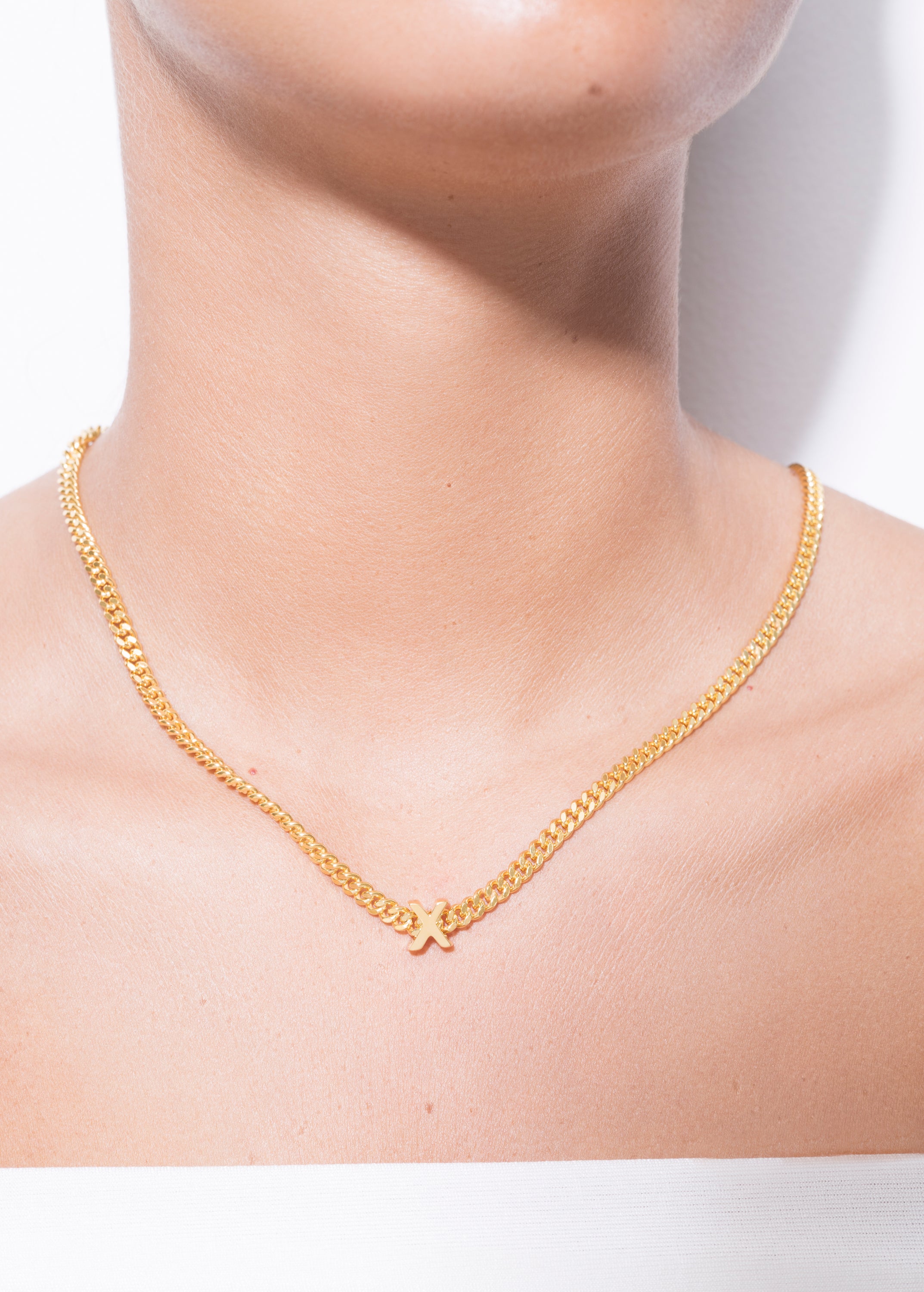 model wearing alphabet necklace with pendant X in gold