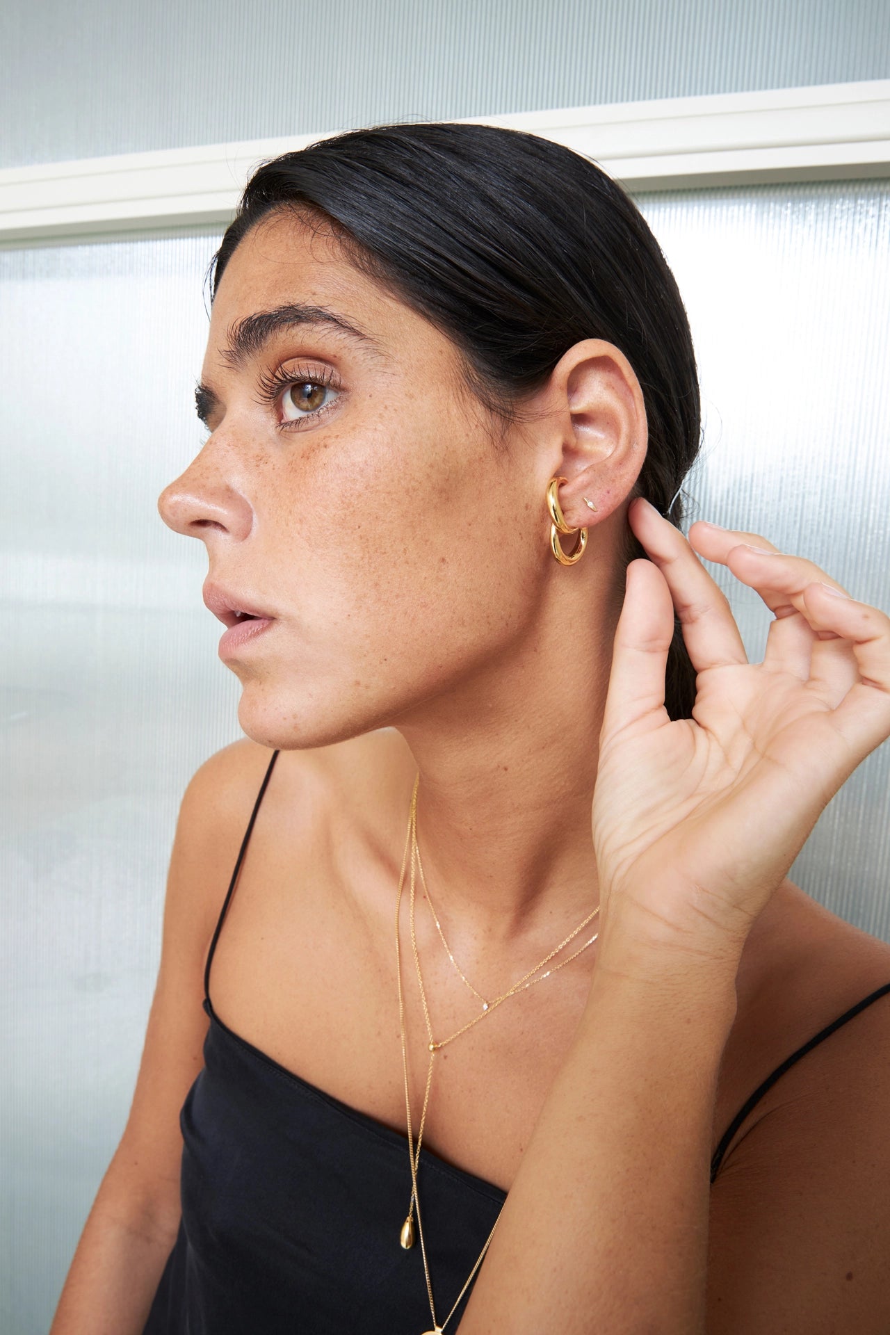 Woman adjusting an earring in front of a mirror