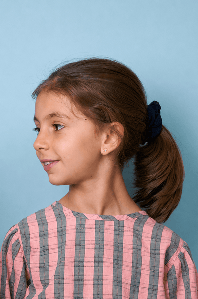 Junges Mädchen trägt ein rosa-grau gestreiftes Shirt vor blauem Hintergrund