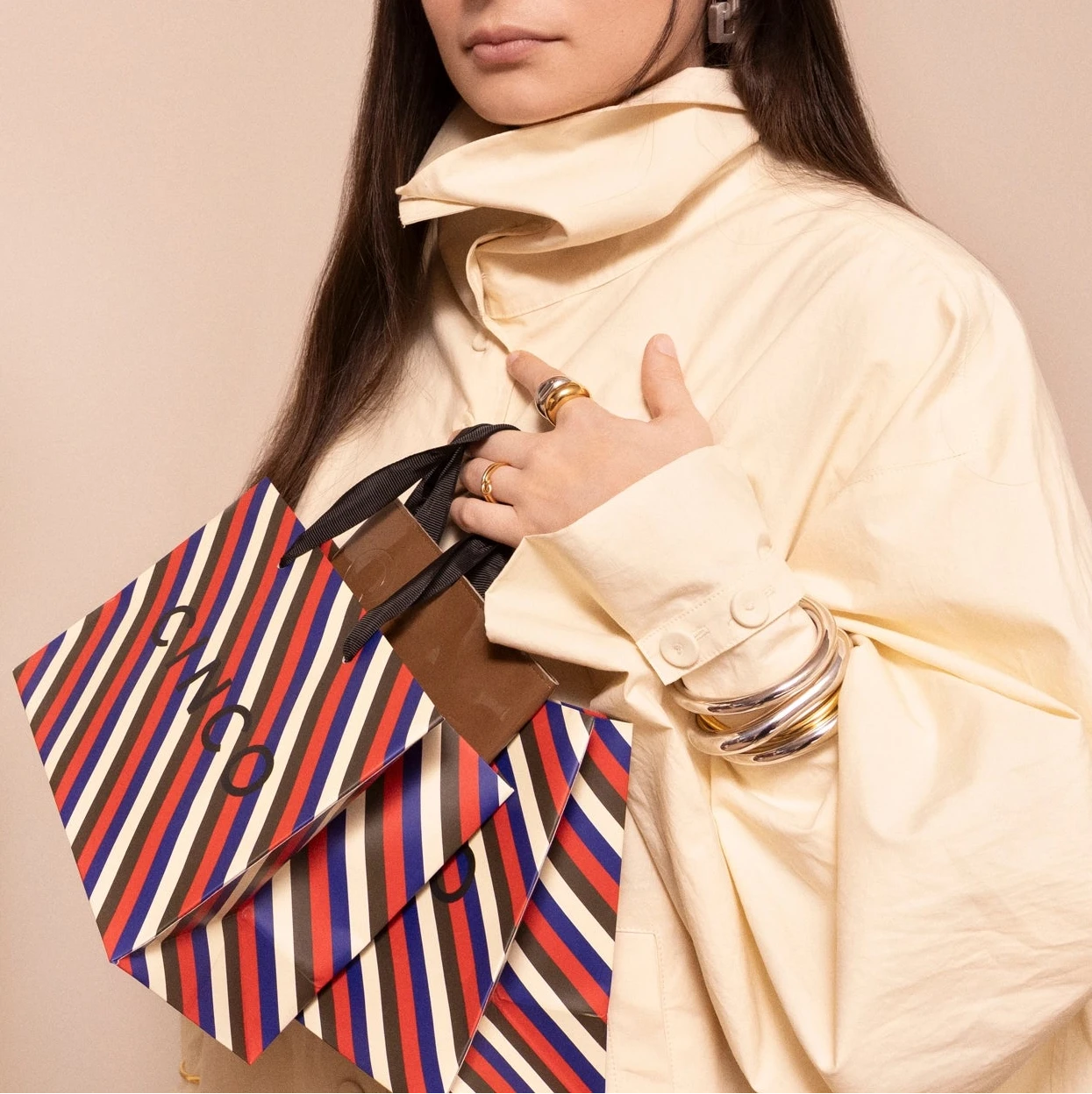 Frau hält eine gestreifte CINCO-Tasche mit Schmuck im Angebot